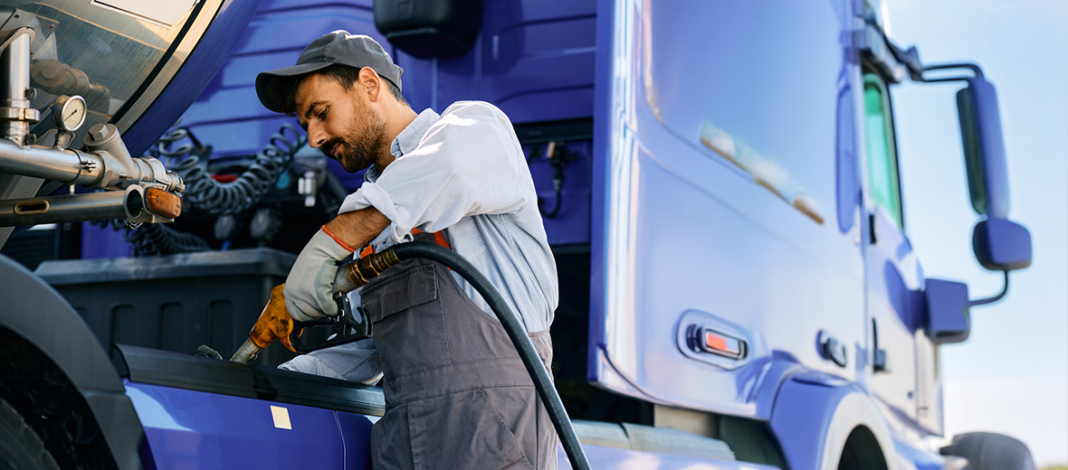 A truck driver using a fleet fuel card while fueling their vehicle.