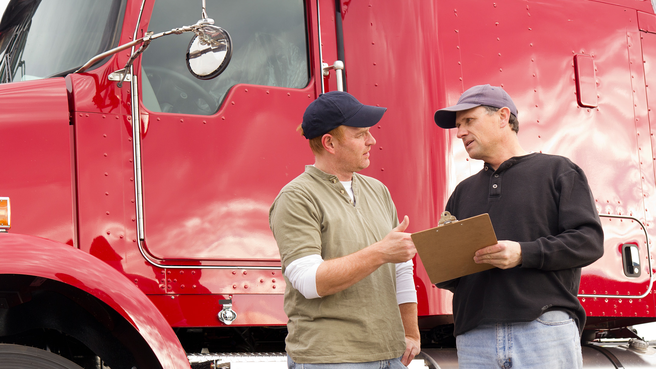 two people standing infront of a red truck