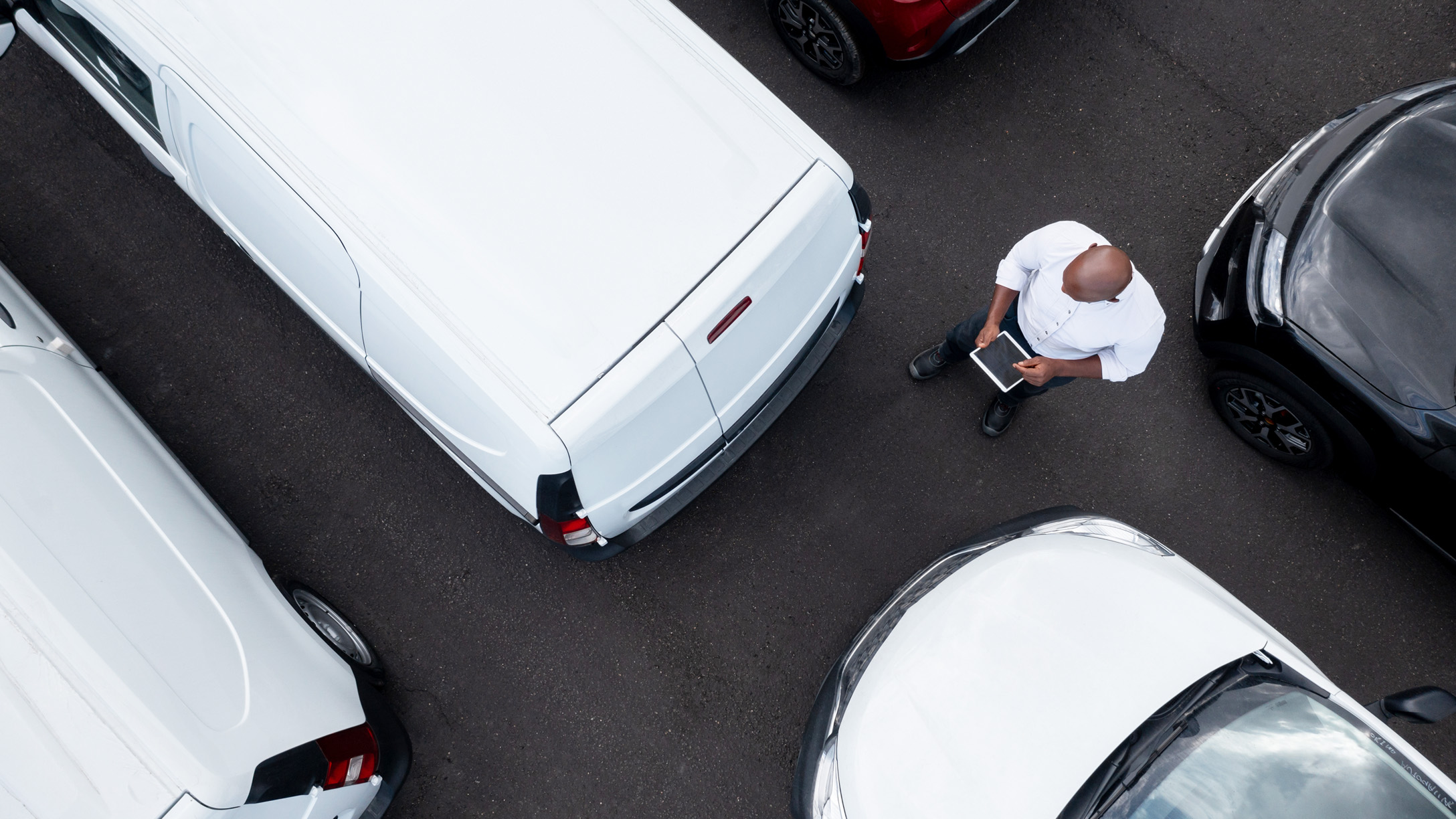 top view of a person standing in between a bunch of parked white vans