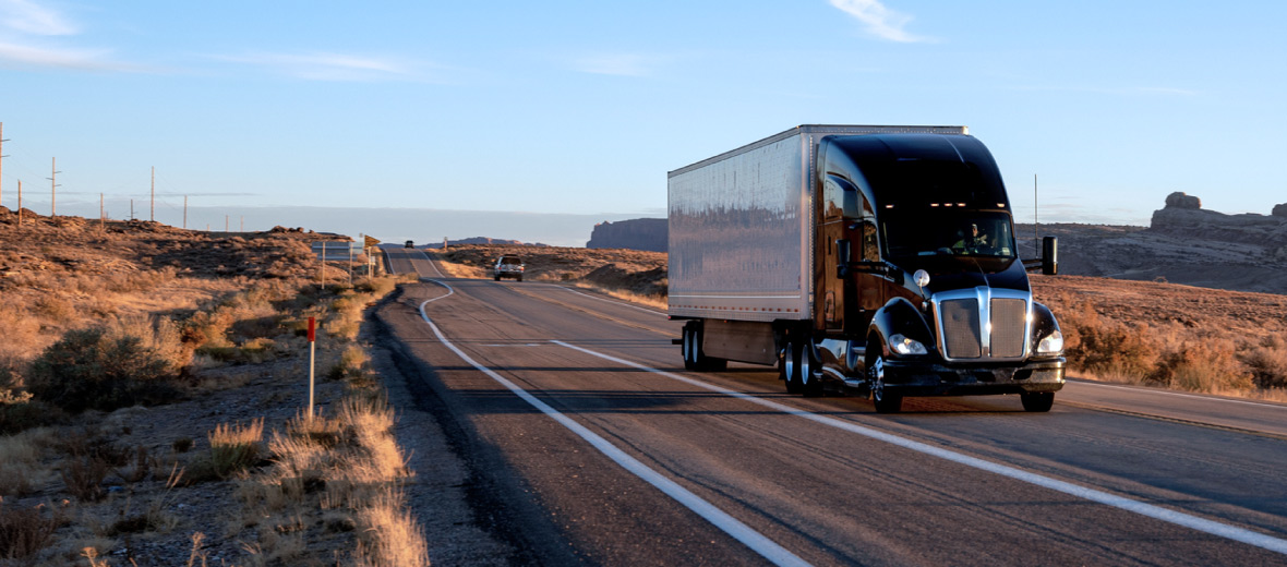 A semi-truck driving down a paved road.