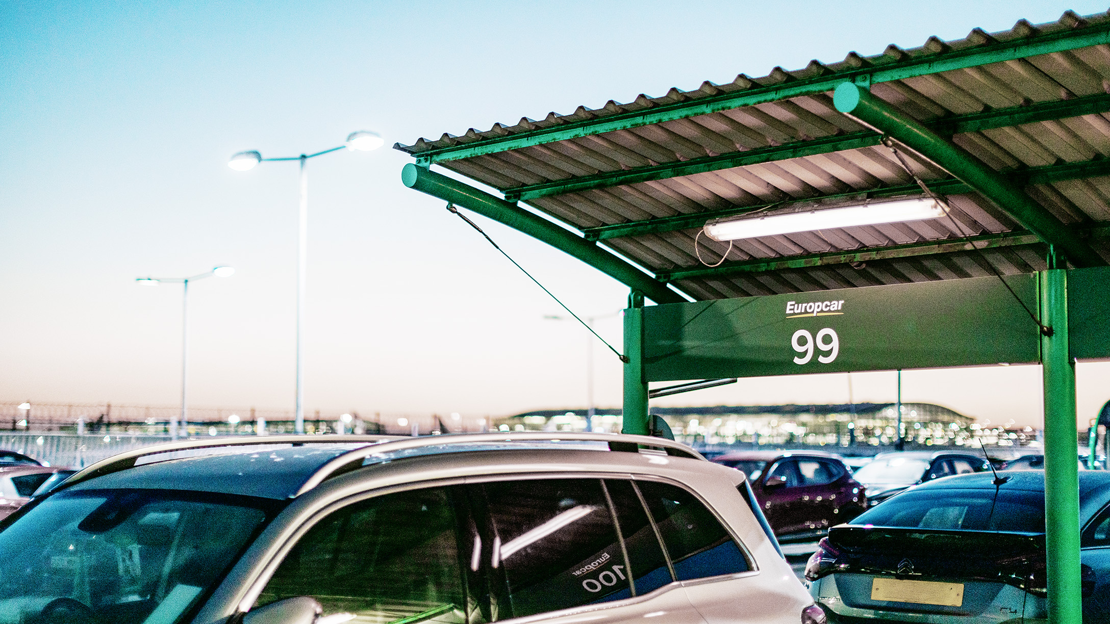 Parcheggio veicoli con logo Europcar in alto su sfondo verde