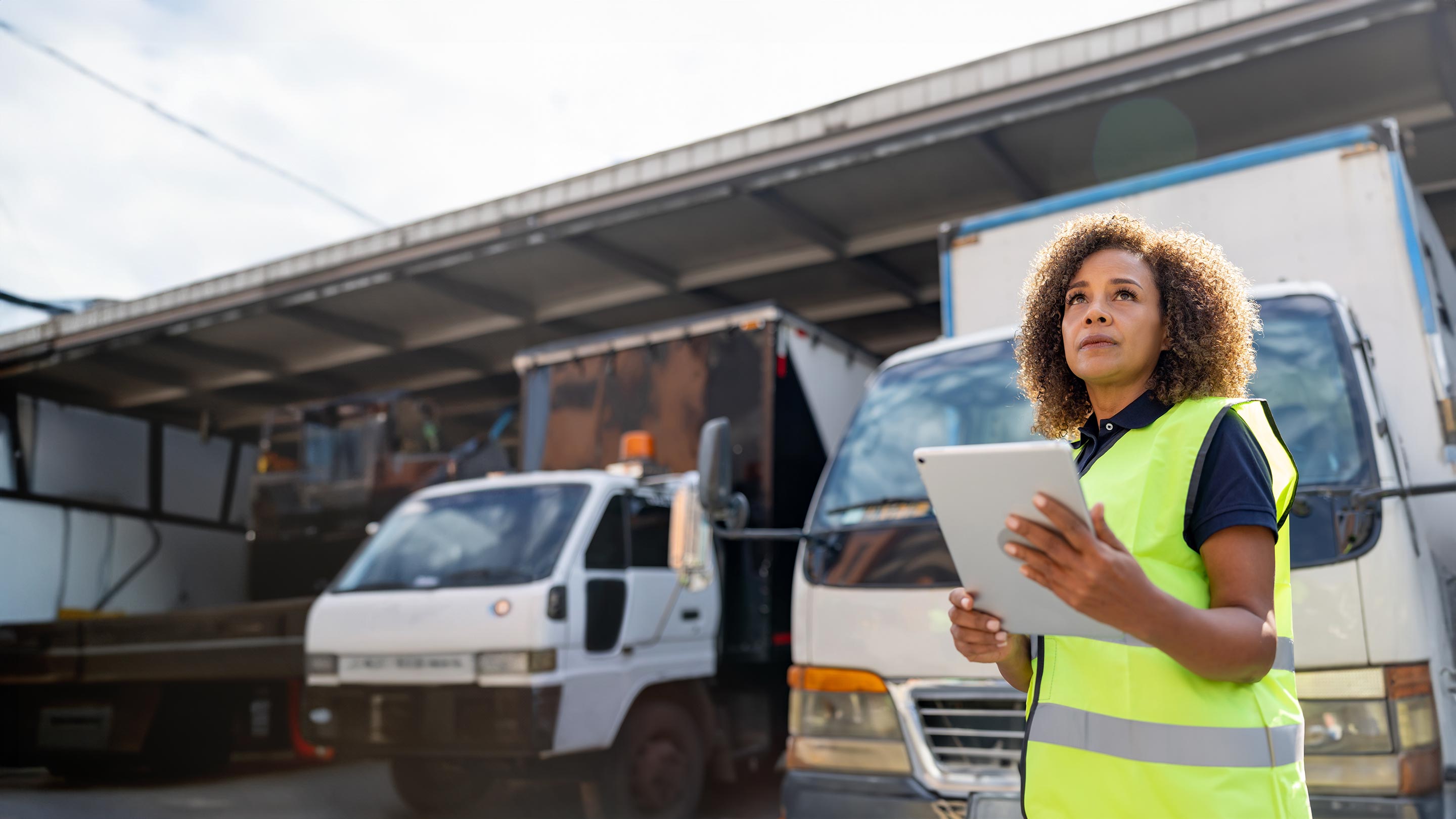 Mujer en una gasolinera eligiendo una manguera de combustible, representando el consumo y gestión eficiente del combustible en flotillas.