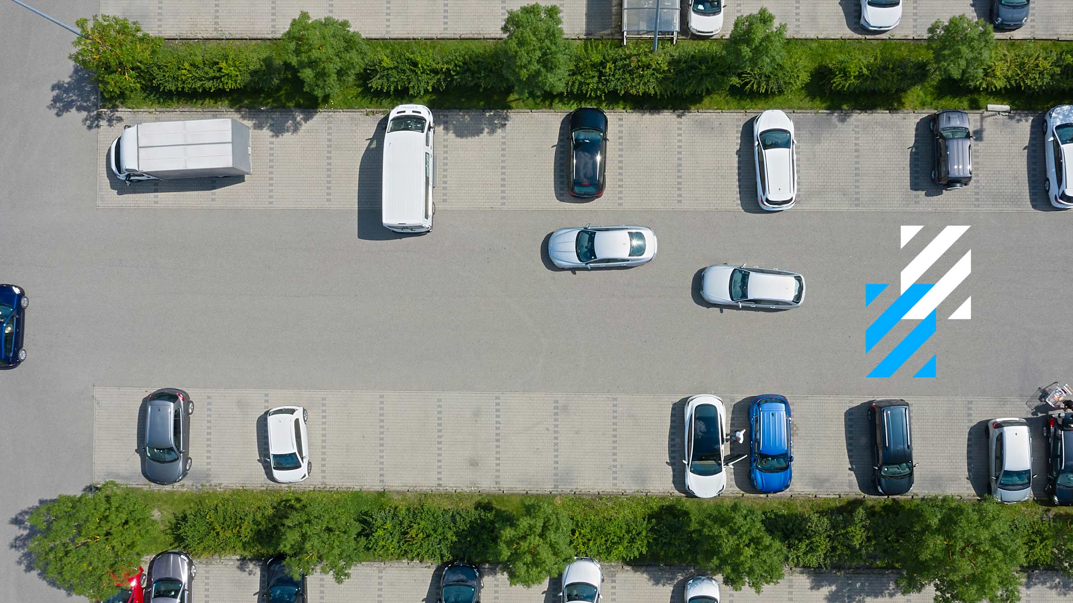 Vista aérea de un estacionamiento con varios autos estacionados, incluyendo vans y sedanes de diferentes colores. Prevenir colisiones con predicción mediante tecnología avanzada