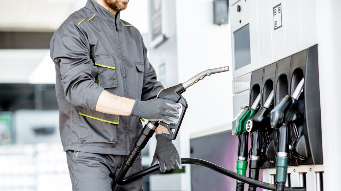 Trabajador llenando un tanque de combustible en una estación de servicio, representando el consumo de combustible y su gestión eficiente.