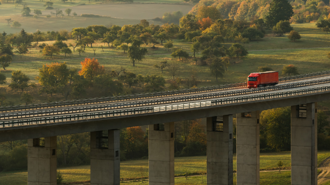 immagine di un veicolo rosso che attraversa un ponte in mezzo alla vegetazione