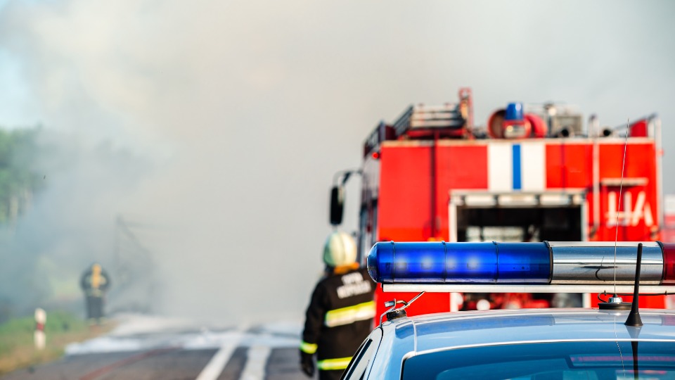 Veicolo dei pompieri fermo in strada davanti al fumo, con un pompiere a lato