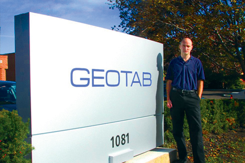 Geotab's CEO Neil Cawse in front of Geotab sign