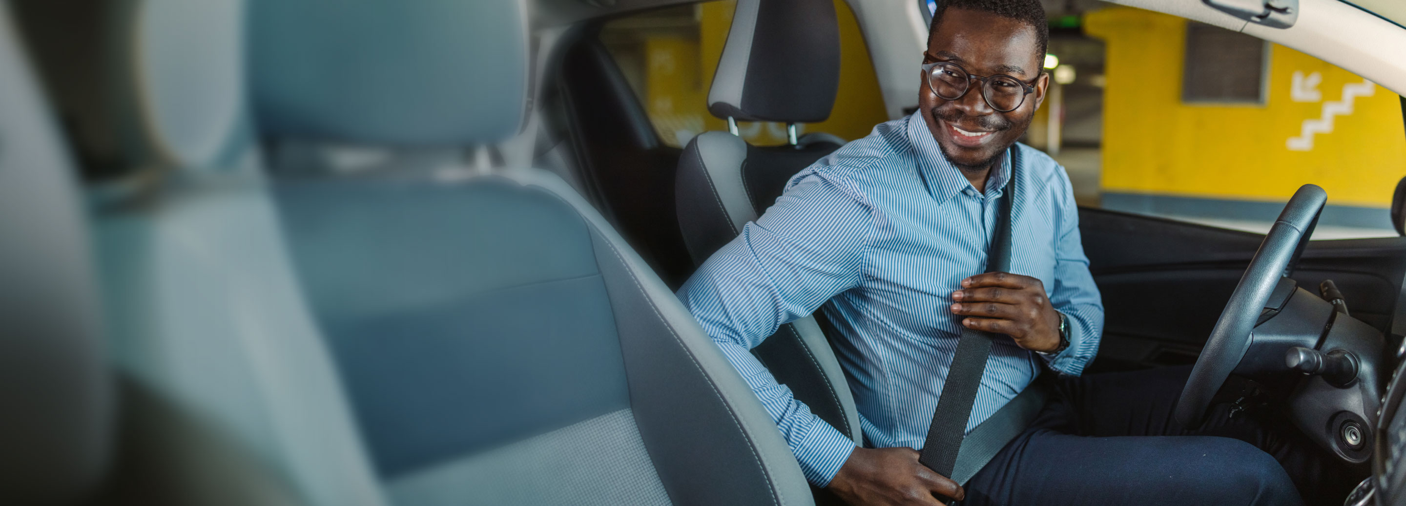 person in drivers seat putting on a seat belt