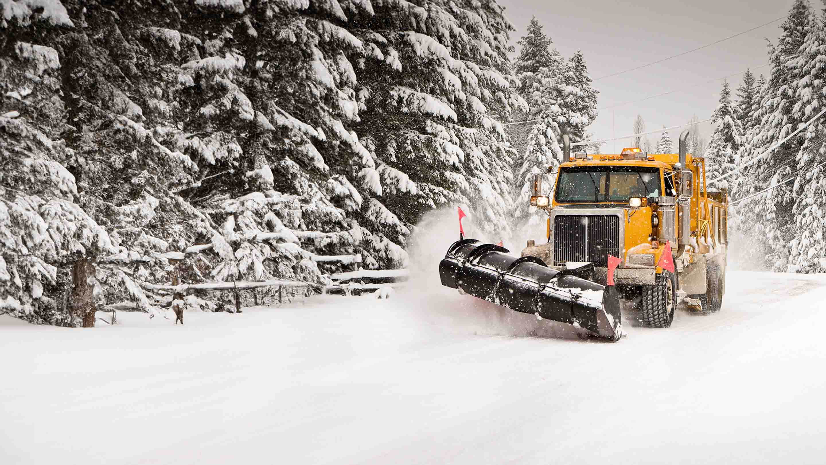 Large snow plow truck driving on snowy road