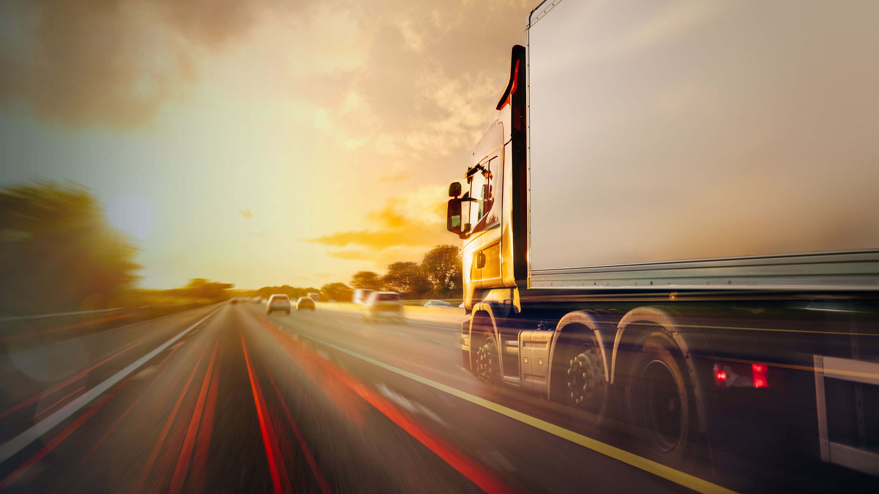 Vehicles driving on a road with sunset in the background